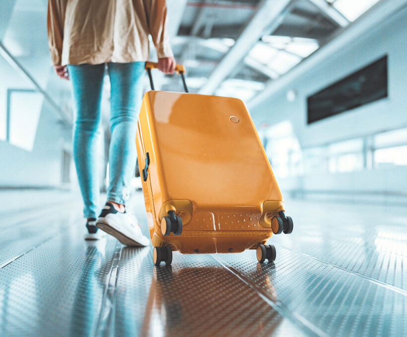 Viajante mulher andando com uma mala amarela no terminal do aeroporto
