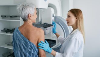 Mulher idosa fazendo mamografia no hospital com técnico médico