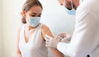 Médico aplicando uma vacina no braço de uma mulher