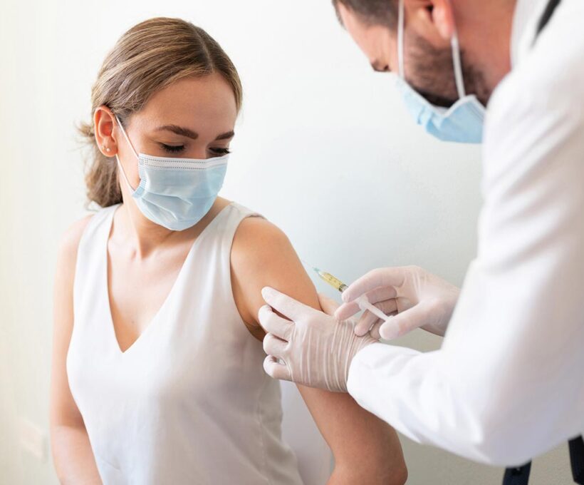 Médico aplicando uma vacina no braço de uma mulher