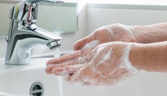 Homem lavando as mãos com água e sabão em pia