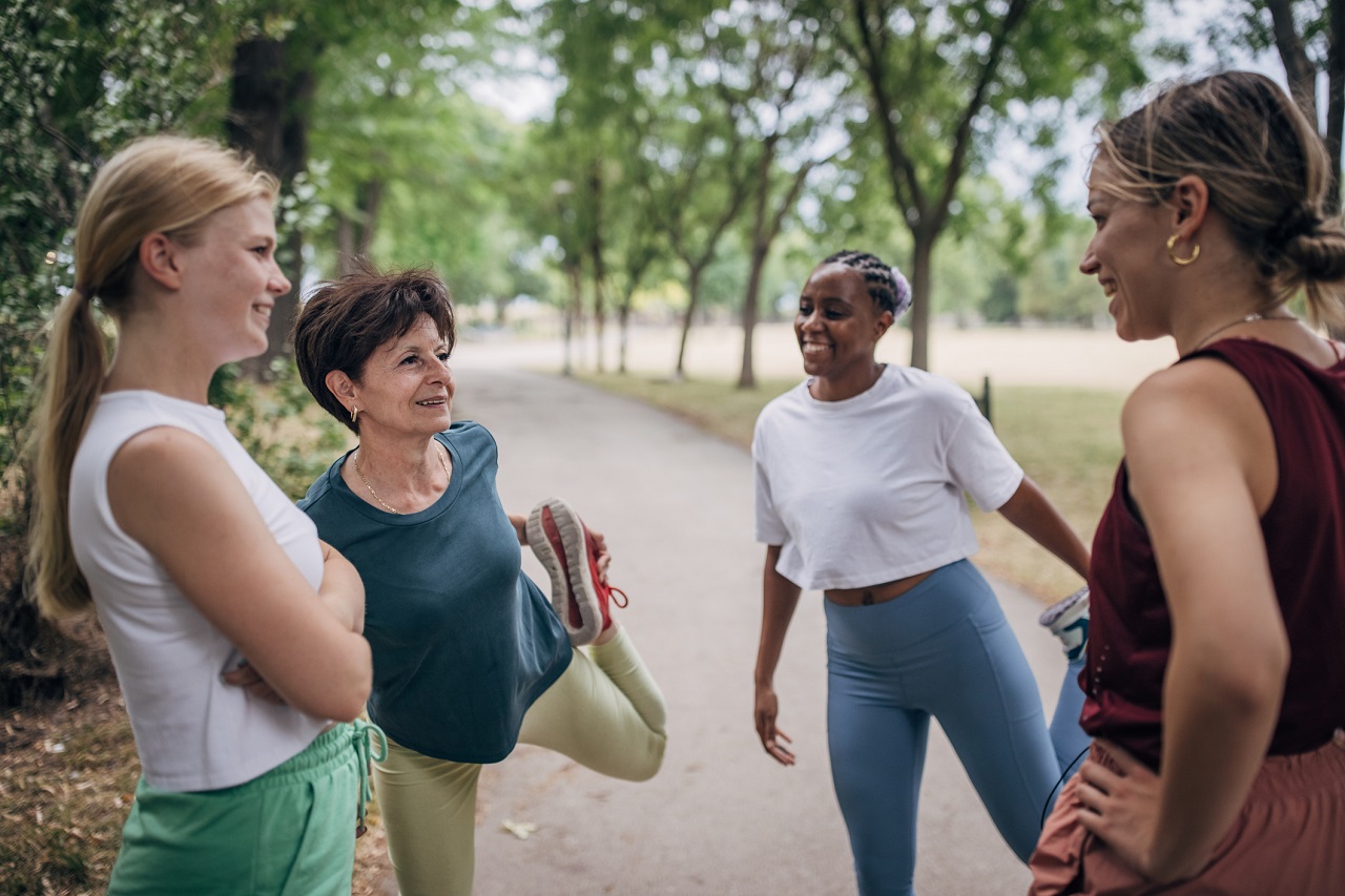 Grupo de quatro mulheres, de diferentes idades, se alongando para se exercitarem e manterem longevidade