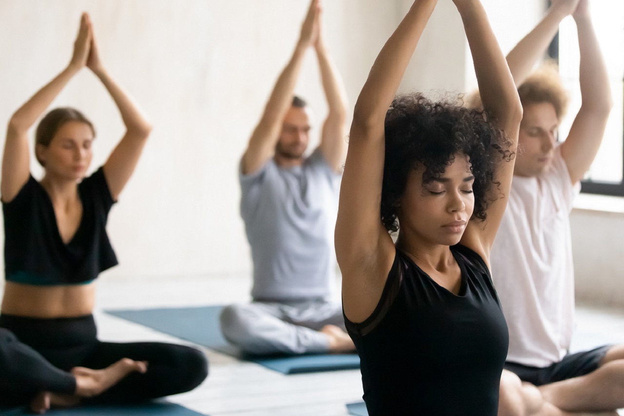 Duas mulheres e dois homens praticando exercício em aula de ioga